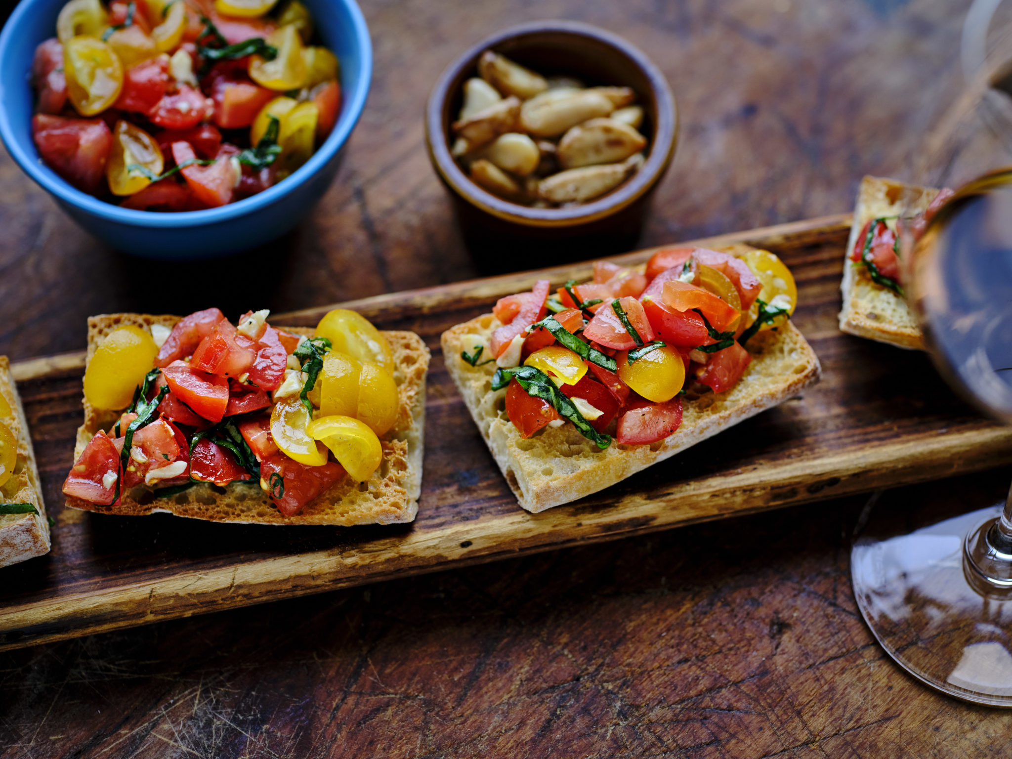 Roasting garlic for this simple summer bruschetta recipe from Annabel Cohen fills your home with a welcoming aroma to greet your guests with.